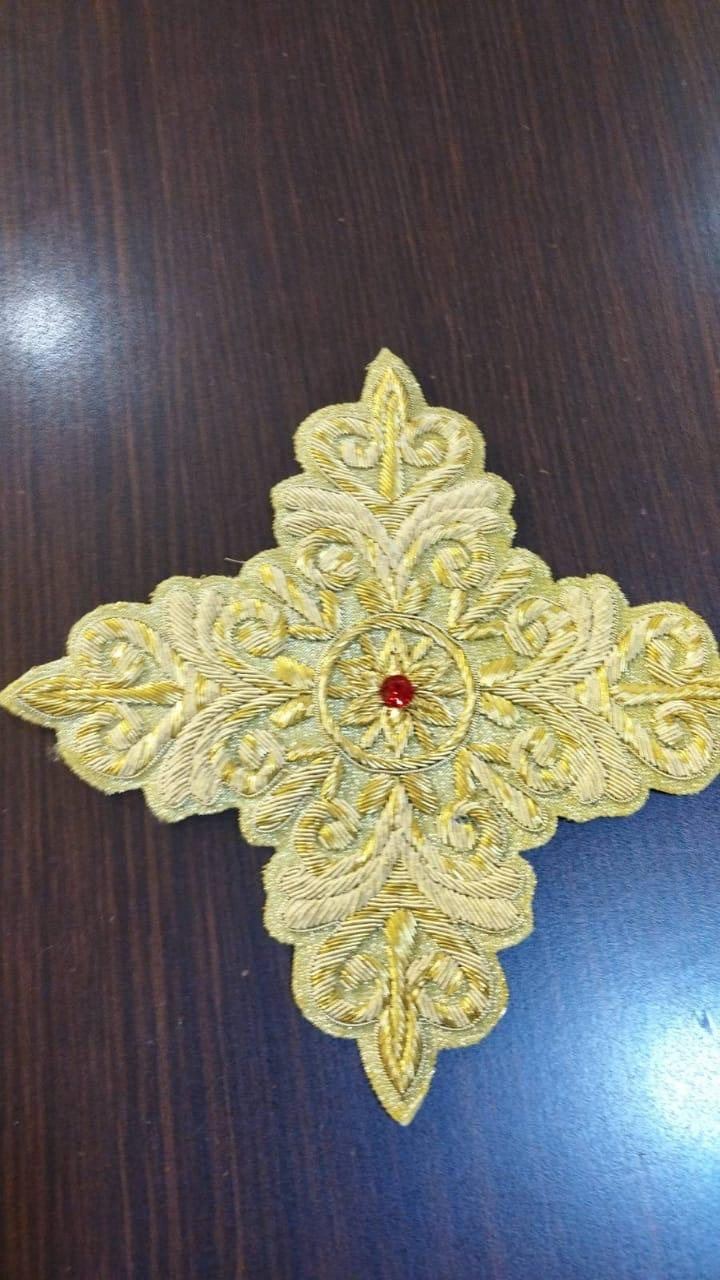 Pale gold cross with scroll work and a ruby centre